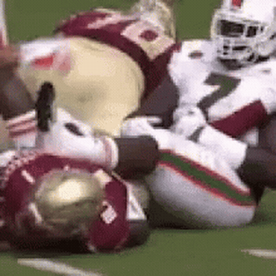 A Group Of Football Players Are Laying On The Ground . GIF