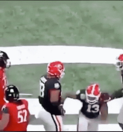 A Group Of Football Players Are Playing A Game On A Field . GIF