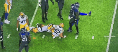 A Group Of Football Players Are Playing A Game On A Field . GIF