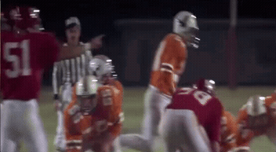 A Group Of Football Players Are Playing A Game On A Field With A Referee . GIF