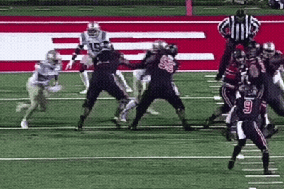 A Group Of Football Players Are Playing A Game On A Field With A Referee . GIF