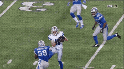 A Group Of Football Players Are Playing A Game On A Field With A Referee In The Background . GIF