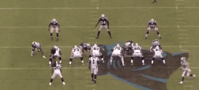 A Group Of Football Players Are Playing A Game On A Field With A Referee In The Middle . GIF