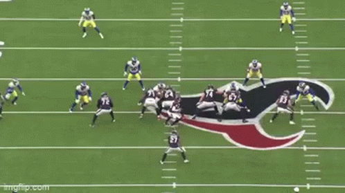 A Group Of Football Players Are Playing A Game On A Field With A Referee . GIF