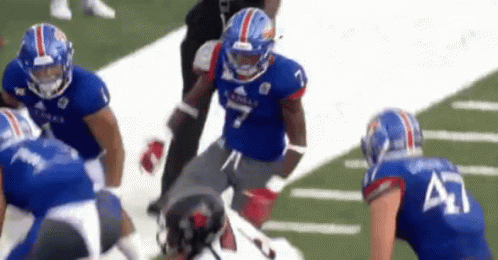 A Group Of Football Players Are Playing A Game On The Field . GIF
