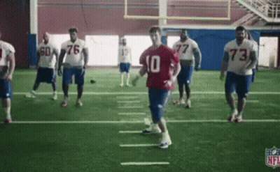 A Group Of Football Players Are Practicing On A Field In A Gym . GIF