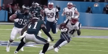 A Group Of Football Players Are Running On A Field . GIF