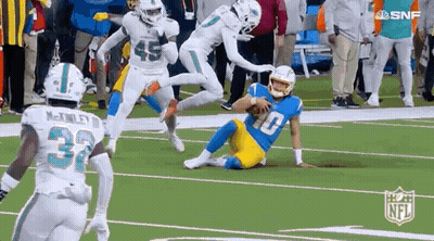 A Group Of Football Players Are Running On A Field . GIF