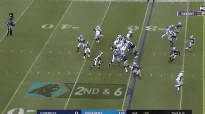 A Group Of Football Players Are Running On A Field While A Man Stands Behind Them . GIF