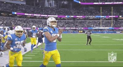 A Group Of Football Players Are Running On A Field With A Referee In The Background . GIF