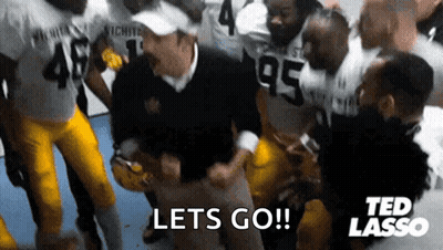 A Group Of Football Players Are Standing Around A Man Who Is Holding A Football And Says Lets Go ! GIF
