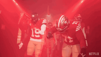 A Group Of Football Players Are Standing In A Tunnel With A Netflix Logo In The Background GIF