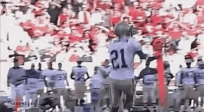 A Group Of Football Players Are Standing In Front Of A Crowd . GIF