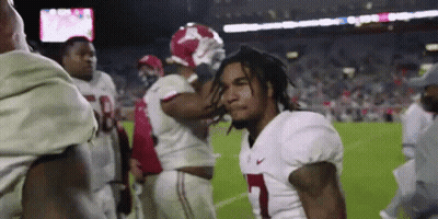 A Group Of Football Players Are Standing On A Field And One Of Them Is Wearing A Number 1 Jersey . GIF