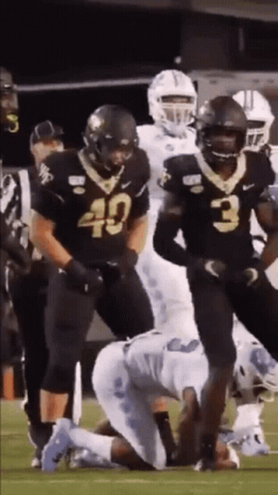A Group Of Football Players Are Standing On A Field . GIF