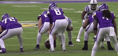 A Group Of Football Players Are Standing On A Field . GIF