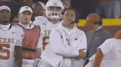 A Group Of Football Players Are Standing On A Field With A Coach Standing Behind Them . GIF