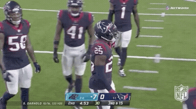 A Group Of Football Players Are Standing On A Field With A Scoreboard In The Background . GIF