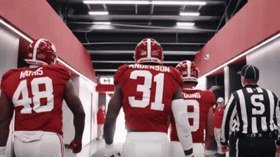 A Group Of Football Players Are Walking Down A Hallway And One Of Them Has The Number 31 On His Jersey GIF