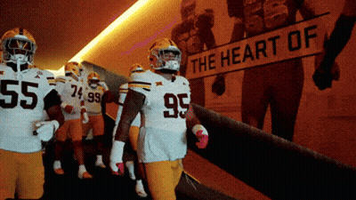 A Group Of Football Players Are Walking Down A Hallway With A Sign That Says The Heart Of GIF