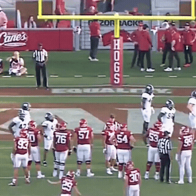 A Group Of Football Players On A Field With A Sign That Says Hogs On It GIF
