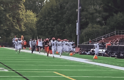 A Group Of Football Players Running On A Field With One Wearing The Number 21 GIF