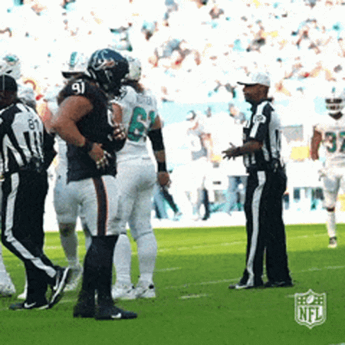 A Group Of Football Players Standing On A Field With A Referee And A Nfl Logo In The Background GIF