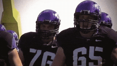 A Group Of Football Players Wearing Purple Helmets And Jerseys With The Number 76 And 65 On Them GIF