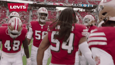 A Group Of Football Players Wearing Red Jerseys With The Number 54 On The Back GIF
