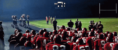 A Group Of Football Players Wearing Red Uniforms With The Number 22 On The Back Stand In Front Of A Scoreboard GIF