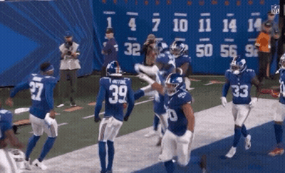 A Group Of Giants Football Players Celebrate A Touchdown GIF