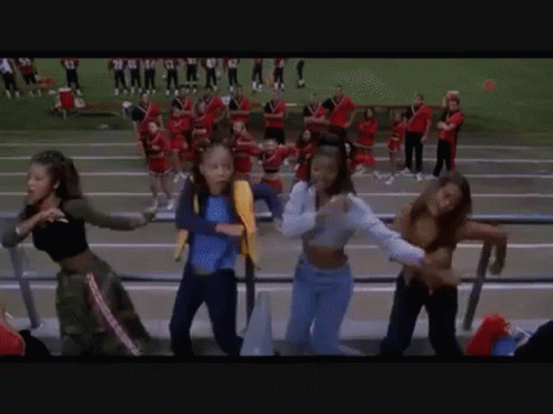 A Group Of Girls Are Dancing In A Stadium While Watching A Football Game . GIF