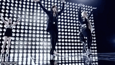 A Group Of Girls Are Dancing In Front Of A Wall Of Lights . GIF