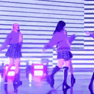 A Group Of Girls Are Dancing On A Stage With Purple Lights GIF