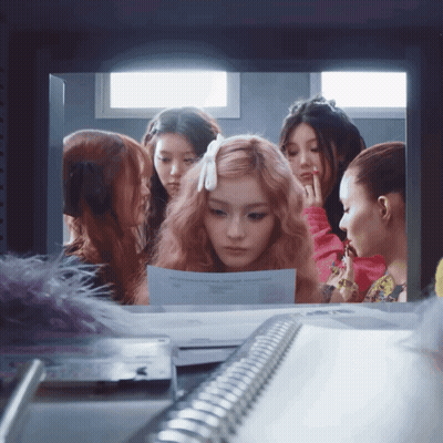 A Group Of Girls Are Looking At A Piece Of Paper That Says ' A ' On It GIF