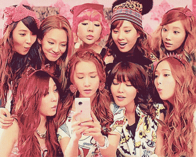 A Group Of Girls Are Posing For A Picture With One Girl Holding A Cell Phone GIF