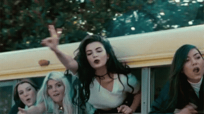 A Group Of Girls Are Riding On The Back Of A School Bus And One Girl Is Pointing At The Camera . GIF