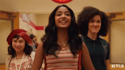 A Group Of Girls Are Standing In A Hallway Holding Hands And Smiling . GIF