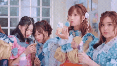 A Group Of Girls Are Standing Next To Each Other And One Of Them Is Holding A Cupcake . GIF