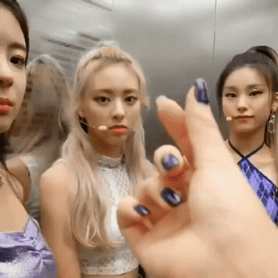 A Group Of Girls Are Standing Next To Each Other In An Elevator . One Of The Girls Is Wearing A Purple Dress . GIF