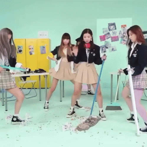 A Group Of Girls In School Uniforms Are Dancing In A Room While Holding Mop Sticks . GIF