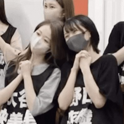A Group Of Girls Wearing Face Masks Are Standing Next To Each Other . GIF