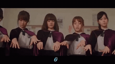 A Group Of Girls Wearing Purple Capes Are Standing Next To Each Other In A Room . GIF