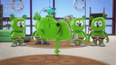 A Group Of Gummy Bears Are Standing In A Room And One Is Doing A Trick GIF