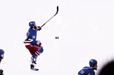 A Group Of Hockey Players Are Playing A Game On The Ice While A Referee Looks On . GIF