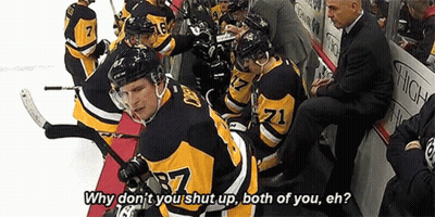A Group Of Hockey Players Are Sitting On A Bench And One Of Them Is Wearing A Jersey With The Number 71 On It . GIF