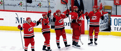 A Group Of Hockey Players Are Standing On The Ice In Front Of An Ad For Raleigh GIF