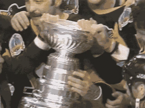 A Group Of Hockey Players Holding A Trophy With The Letter T On It GIF