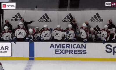 A Group Of Hockey Players Sit In Front Of A Wall That Says American Express On It GIF