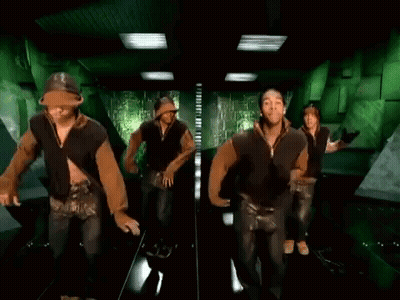 A Group Of Men And Women Are Dancing In A Hallway . GIF